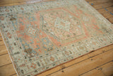 A full length angled view of a distressed Persian Veece rug in rose, silver, and terracotta.