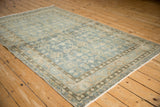 Angled view of a vintage Persian Hamadan rug highlighting its distressed low pile and allover design.