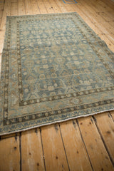 Distressed low pile and meandering vine border on a vintage dusty blue Hamadan rug.