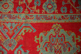 The hand-knotted texture of a vintage Oushak showing even wear across its red and sky blue motifs.