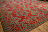 Vintage Oushak carpet corner showing the detailed floral border and low, even-worn pile.