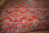 Perspective view of a vintage Oushak's repeating blue medallions on a low-piled pomegranate red field.