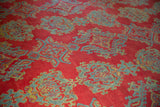 Close-up of blue and gold hook-and-latch medallions on the red, evenly worn pile of a vintage Oushak.
