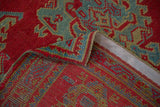 Folded corner of a red Turkish Oushak carpet showing its hand-knotted back and restored side selvage.
