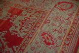 Antique Oushak rug border showing palmette vine motifs in red, slate blue, and hints of gold.