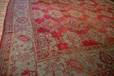 Angled view of an antique Oushak's repeating medallions and meandering palmette border.