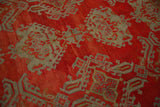 Intricate hook-and-latch motifs in oxidized silver and slate blue on the low pile of an antique Oushak rug.