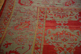 Intricate boteh and palmette designs in red and dusty slate blue on the corner border of an antique Oushak.