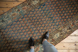 A view from above of a distressed Serbend runner, showing its scale and the texture of its boteh pattern.