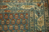 Corner of a distressed Persian runner showing staggered botehs and a meandering vine border.