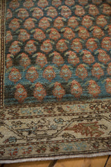 Staggered rose and blue botehs and the meandering vine border of a distressed Persian rug.