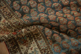 Detailed view of the worn boteh pattern and geometric border on a hand-knotted Serbend rug.