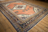 Angled view of a vintage Lilihan carpet's geometric medallion and abrashed copper rose field.