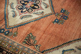 A vintage Lilihan rug's serrated medallion corner against its abrashed pale copper rose field.