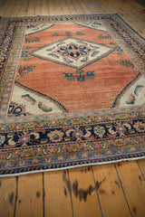 Low-angle perspective of a vintage Lilihan carpet's abrashed copper rose field and diamond medallion.