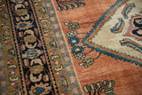 Close-up of a vintage Lilihan's serrated spandrel, navy border, and copper-rose field.