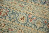 Close-up showing the distressed, low-pile texture with rust botehs on a dusty blue and cream field.