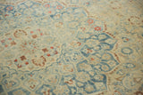 Evenly worn knot heads on a Persian carpet with dusty blue and rust sprawling vine motifs.