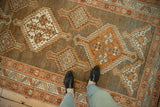 Overhead view of a distressed Kurd rug's stepped medallions in rust, ivory, and coffee brown tones.