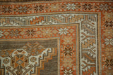Rust, ivory, and coffee brown pinwheel floral motifs within the geometric borders of a distressed Kurd rug.