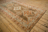 Angled perspective of a vintage distressed Kurd rug with stepped medallions on an abrashed brown field.