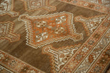 Angled detail of a stepped medallion with rust and ivory pinwheel floral elements on a distressed Kurd rug.