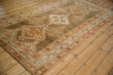 Angled view of a vintage Kurd rug with oversized stepped medallions in rust and brown.
