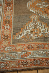 Geometric stepped medallion and pinwheel border in rust, ivory, and brown on a distressed Kurd rug.