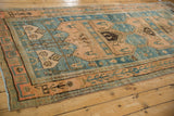Angled view of a distressed Bijar runner's heavily abrashed sky blue ground and primitive rose border.