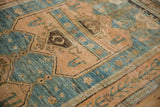 Angled close-up of a distressed Bijar rug highlighting its worn pile and abrashed blue and rose pattern.
