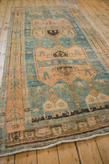 Angled view of a distressed Bijar runner's primitive medallions in sky blue and rose.