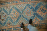 Asymmetric diamond medallions and checkered details in dusty blue and coffee brown on a distressed runner.