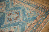 Close-up on the splayed checkered diamonds and arrowed finials of a distressed Malayer rug.