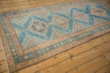 A vintage Malayer runner seen from an angle, highlighting its distressed low pile and geometric design.