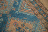 Detail of scattered human and bird figures on the dusty blue field of a distressed Malayer Persian rug.