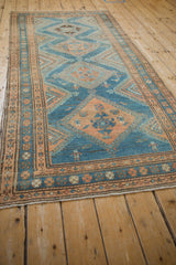 Long angled view of a vintage distressed Malayer runner with blue and tan geometric diamonds.