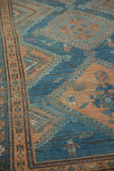 Worn hand-knotted texture showing stylized human figures in dusty blue and coffee brown on a vintage Malayer rug.