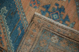 A folded corner reveals the hand-knotted foundation and side cord selvage of the vintage Malayer rug.