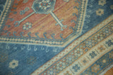 Distressed low pile with dusty blue hook-and-latch motifs on an abrashed ruby red field.