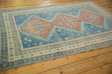 Angled view of a vintage Caucasian rug's distressed pile and repeating geometric medallions.