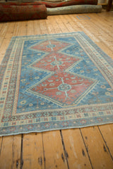Angled perspective of a distressed Caucasian rug showing its triple pomegranate medallions.