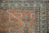 Detailed corner of a distressed Malayer rug with terracotta stepped motifs and intricate blue borders.