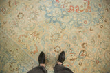 The worn, hand-knotted texture of a Persian Tabriz with slate blue scrolled vines and cinnabar red blossoms.