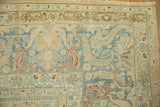 Corner of a distressed Tabriz carpet with scrolled vines and leaves in slate blue and cinnabar red.