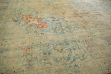 Angled view of the distressed Tabriz carpet, detailing its low pile and mostly even wear.