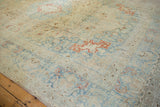 Distressed corner of a vintage Tabriz rug with time-softened slate blue and cinnabar red florals.