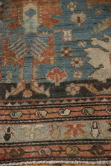 Distressed texture and exposed knot heads of a Persian rug with a boteh border.
