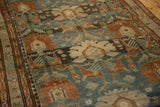 Close view of the worn pile, revealing palmette and animal motifs in dusty teal and chestnut.