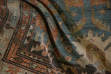 The supple drape and worn texture of an antique Persian rug in muted teal and chestnut hues.