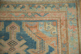 Distressed Malayer rug corner with worn pile, geometric borders, sky blue and rose hues.